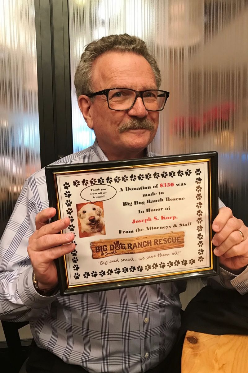 Joseph Karp shows off his holiday present from attorneys and staff: a donation in his honor to Big Dog Ranch Rescue 